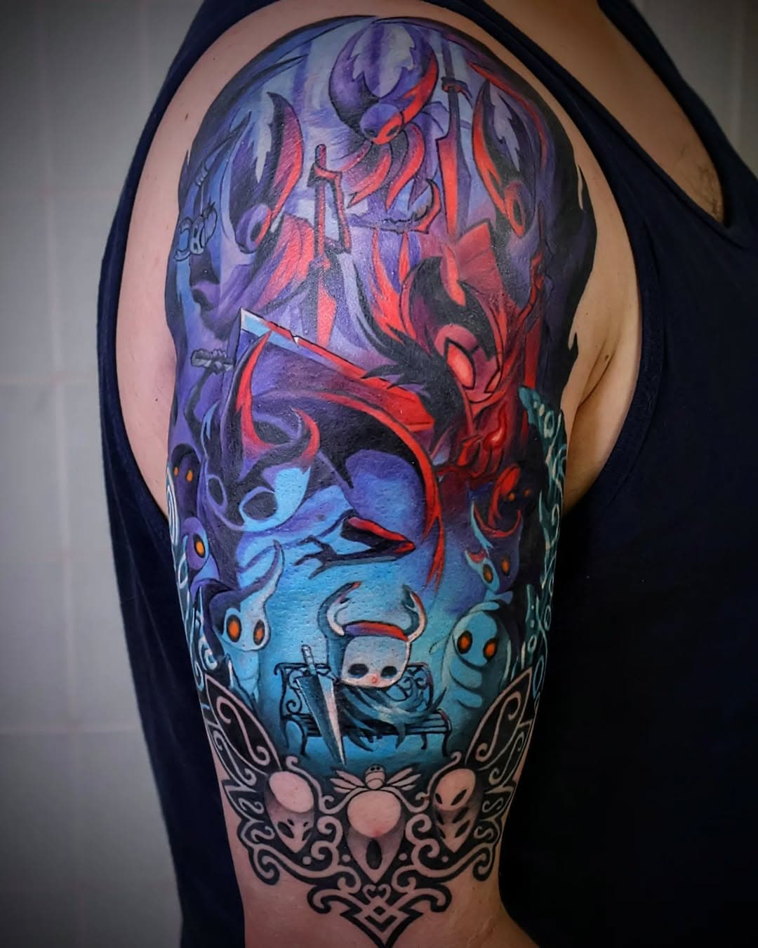 H o l l o w  K n i g h t.

Thank you John for trusting me with this project. I had a wonderful time re-exploring Hollow Knight while I prepped the design; it felt necessary to immerse myself in its atmosphere again to really try to capture it in the tattoo.

John's concept for the project was to depict a moment of peace in Hallownest amidst a dangerous world full of enemies and challenges. To have the Knight taking a break on a bench, a brief respite before they resume their journey, was such a fun idea and I really wanted to portray that vibe through the colors as much as the subjects.

For those in the know, there's a lot here to see and enjoy. There's a small Easter Egg that gave me no small amount of joy to include. Given the sheer amount of enemies and bosses in Hollow Knight, we narrowed it down to some of John's favourites, including the Mantis Lords at the top, Grimm of the Grimm Troupe, one of the Watcher Knights, and then a few of the more common bugs seems around Hallownest. Finally, as a framing device, we've used the rough shape of a Great Wyrm's horns on either side as well as the three masks of the Dreamers.

I hope you all enjoy! It was a challenging piece and I'm thrilled I had the opportunity to tattoo some Hollow Knight stuff again. Big thanks to John for an awesome concept and for sitting like a rock through some long days.

--------

#hollowknight #mantislords #videogametattoos #phillytattooartists
#crownandfeathertattoo #illustrativetattoos #customtattoos #nerdytattoos #silksong #hollowknightfanart #lordlexantattoos