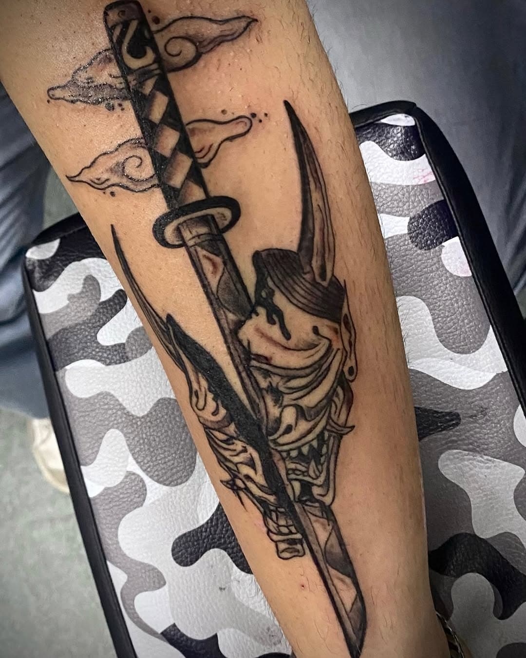 tatuaggio propiziatorio atto ad allontanarle il male; in questo caso rappresentato da una Katana che taglia in due una maschera Oni. Può rappresentare anche il trionfo del bene sul male o la forza d’animo e la perseveranza con nobili scopi.