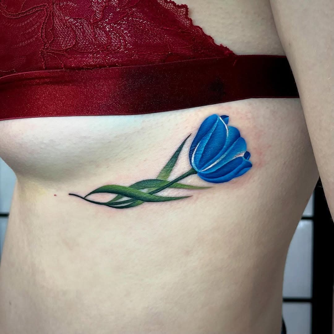 Hellooo! Absolutely love tattooing tiny florals💙. Thank you so much @krystaljen123 for coming to me for this beautiful, blue Tulip 🌷🩵✨
.
Wondering where exactly I am based? I am now offering out tattoo appointments from BOTH the following locations.
.
 **BIRMINGHAM- 34 Tenby street, Jewellery quarter, B1 3EE 🎨🔥**
.
**CHESHIRE- 5 Welles Street, Sandbach, CW11 1GT 🎨🔥**
.
To enquire about getting booked in and to discuss your design ideas in either location, please EMAIL me at jamainepalin_ink@outlook.com with your enquiry, or to book your FREE telephone consultation with me please click on the reservio link in my bio or below to select the availability shown that suits your schedule to secure your slot at http://tropikalcoconuttattoo.reservio.com 🎨✨. I look forward to hearing your design ideas☺️
.
Credit and many thanks goes to @kilipictures for the Videography, it’s been so much fun working with you guys! 🎥
.
#artistsoninstagram #fusionink #colourtattoo #colourtattoos #colourrealism #colourrealismtattoo #worldfamousink #kwadroncartridges #kwadron #watercolourtattoo #floraltattoo #colourportrait  #colourportraittattoo #artistsofinstagram #watercolour #ladytattooers #ladytattooer #uktattoo #uktattooist #birminghamtattoo #manchestertattoo #tattoo #tattoos #cheyennetattooequipment #killerink #butterluxe_uk #stencilstuff #tuliptattoo #tulip